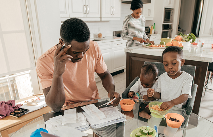 Family in the kitchen, father using a calculator and looking at bills